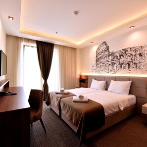 Una habitación de hotel con una cama, un escritorio, una silla, una mesita de noche y un mural en la pared.
