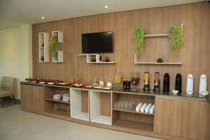 A modern kitchen with wooden cabinetry, a flat-screen TV, and various food and drink dispensers. - Atlantico Sul Hotel Porto de Galinhas (Ipojuca)