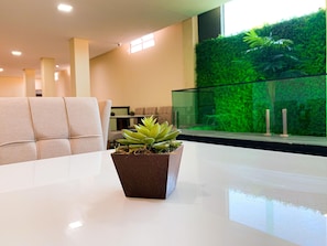A modern interior with a white table, a potted succulent, and a green wall with plants. - Atlantico Sul Hotel Porto de Galinhas (Ipojuca)