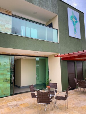 A modern building with a glass entrance, outdoor seating area with wicker chairs, and a green wall with a star and anchor design. - Atlantico Sul Hotel Porto de Galinhas (Ipojuca)