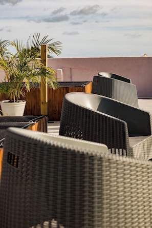 Outdoor wicker furniture arranged on a rooftop terrace with a potted plant and a wooden fence in the background. - Atlantico Sul Hotel Porto de Galinhas (Ipojuca)