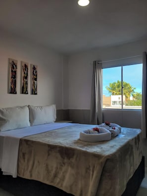 A hotel room with a large bed, a view of palm trees, and three abstract paintings on the wall. - Atlantico Sul Hotel Porto de Galinhas (Ipojuca)