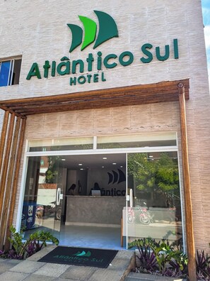 The exterior of the Atlantico Sul Hotel with a modern facade, large glass entrance, and a visible reception area inside. - Atlantico Sul Hotel Porto de Galinhas (Ipojuca)