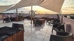A rooftop terrace with outdoor seating, a large shade sail, and a view of the sunset. - Atlantico Sul Hotel Porto de Galinhas (Ipojuca)