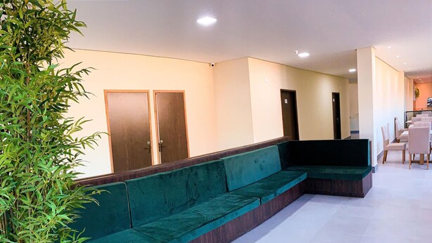 A modern waiting area with a green sofa, a potted plant, and a staircase leading to a dining area. - Atlantico Sul Hotel Porto de Galinhas (Ipojuca)