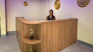 A reception desk with a nameplate, a clock, and decorative wall art. - Atlantico Sul Hotel Porto de Galinhas (Ipojuca)