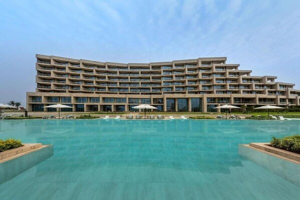 Un hotel de varios pisos con una piscina al frente.