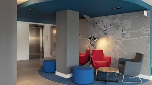 A modern lobby with a curved blue ceiling, a map wall, and seating areas with red and grey chairs. - Holiday Inn Express & Suites Deventer (Deventer)