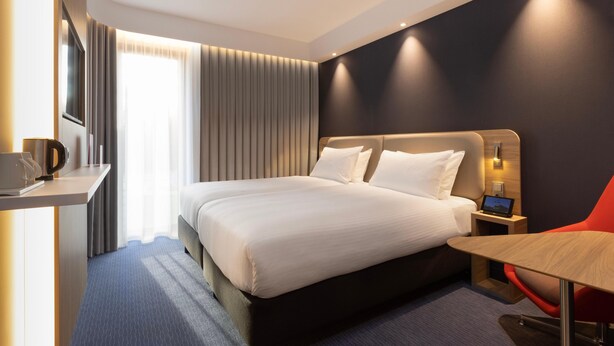A modern hotel room with a large bed, a desk, a chair, and a TV. - Holiday Inn Express & Suites Deventer (Deventer)