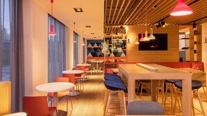 A modern interior with wooden floors, tables, and chairs arranged in a spacious layout. - Holiday Inn Express & Suites Deventer (Deventer)