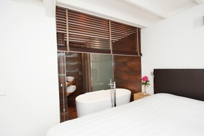 Ein modernes Badezimmer mit einer freistehenden Badewanne, einer Duschkabine aus Glas und einem Holzwaschtisch.