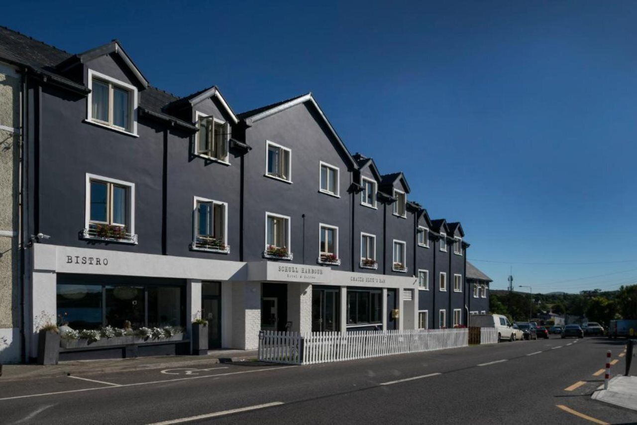 En rad moderna byggnader med butikslokaler där det står ”BISTRO” och ”SCHOLL HARBOUR” på skyltarna.