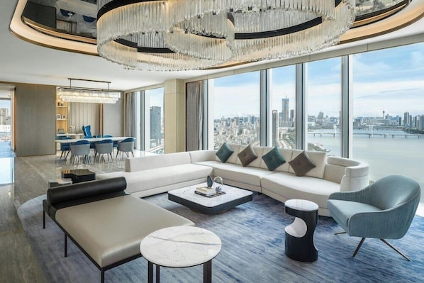 A modern living room with a large sofa, a coffee table, and a view of a cityscape through large windows. - Renaissance Zhuhai Hotel (Zhuhai)