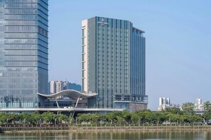 Um hotel moderno e imponente com design elegante, destacando uma estrutura vertical marcante e um elemento arquitetônico curvo original na base.