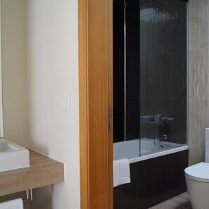 Ein modernes Badezimmer mit einem Holzkosmetikschrank, einer Duschkabine aus Glas und einer Toilette.