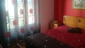 Quarto com cama, mesa de cabeceira, telefone e um quadro na parede.