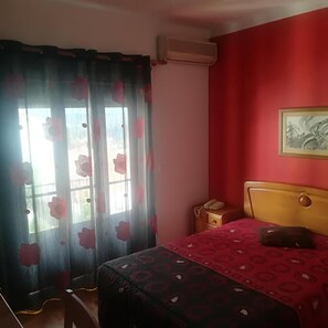 A bedroom with a bed, a nightstand, a telephone, and a painting on the wall. - Hotel Conforto Latino (Abrantes)