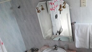 Casa de banho com lavatório de mármore, espelho e banheira.