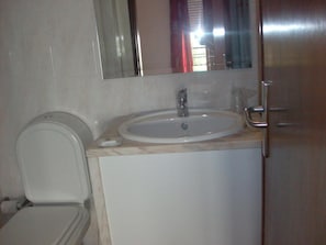 A bathroom with a toilet, sink, mirror, and a cabinet. - Hotel Conforto Latino (Abrantes)