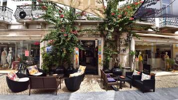 Un espace extérieur aménagé avec des meubles en osier et des plantes en pot, situé devant un hôtel-boutique.