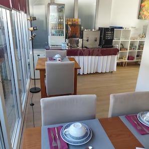 Un coin repas avec une table dressée pour deux personnes, un réfrigérateur, un four à micro-ondes et une machine à café.