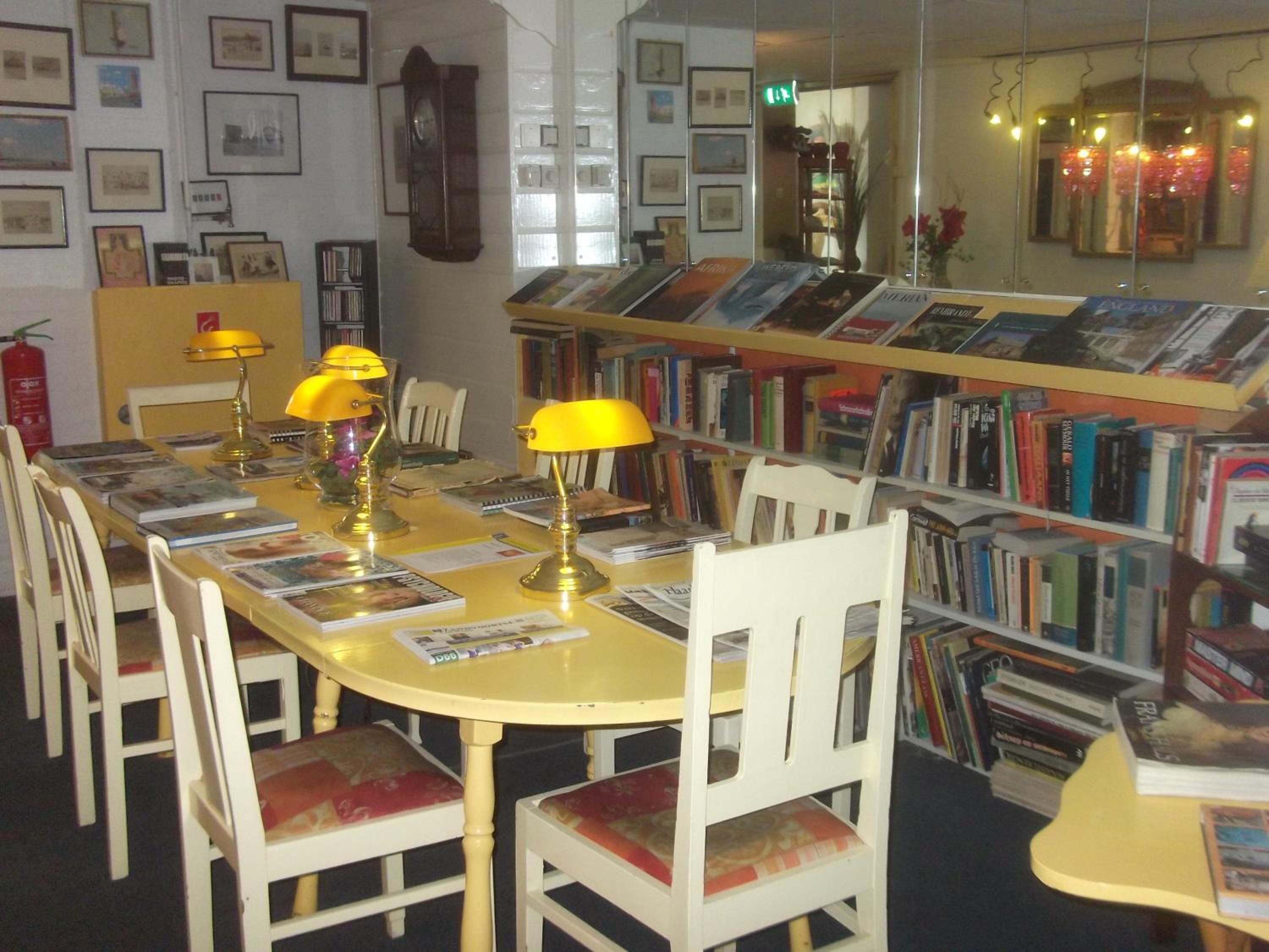 Een bibliotheek met een lange tafel, stoelen en boekenplanken vol boeken.
