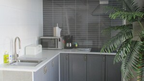 A modern kitchen with grey cabinets, a stainless steel sink, a microwave, and a coffee maker. - Hotel Hoogland Zandvoort Aan Zee (Zandvoort)