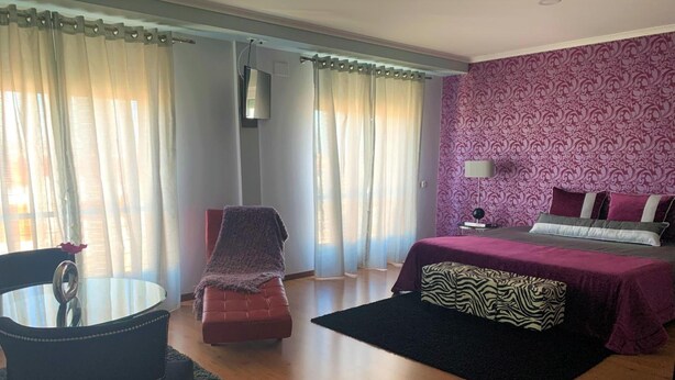 A bedroom with a bed, a chair, a table, and a TV. - Hotel Gameiro (Entroncamento)