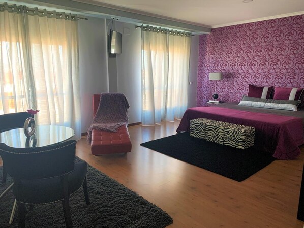A bedroom with a bed, a chair, a table, and a TV. - Hotel Gameiro (Entroncamento)