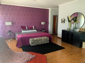 A bedroom with a bed, two bedside lamps, a dresser, a mirror, and a vase with flowers. - Hotel Gameiro (Entroncamento)