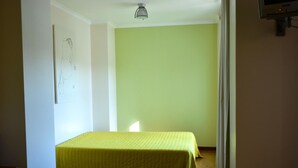 A room with a bed, a light-colored wall, and a door leading to another space. - Hotel Gameiro (Entroncamento)