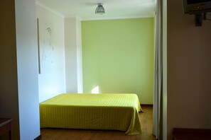A room with a bed, a light-colored wall, and a door leading to another space. - Hotel Gameiro (Entroncamento)