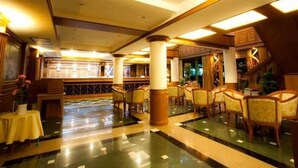 A spacious lobby with a polished floor, wooden columns, and a seating area with chairs. - Zaza Hotel (Samut Prakan)