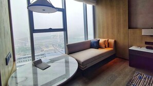 A modern room with a large window, a round glass table, a sofa with cushions, and a ceiling light. - Courtyard by Marriott Luoyang (Luoyang)