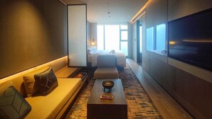 A modern hotel room with a sofa, a bed, a TV, and a large window providing a view. - Courtyard by Marriott Luoyang (Luoyang)