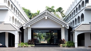 A modern building with a symmetrical facade, featuring a central entrance with a glass door and a decorative roof. - Pooh Beach Resort and Spa (Pattaya)