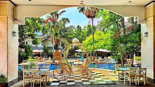 An outdoor pool area with a checkered floor, surrounded by tropical plants and a decorative archway. - Pooh Beach Resort and Spa (Pattaya)