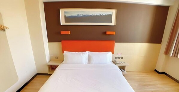 A hotel room with a bed, a nightstand, a telephone, and a painting on the wall. - 7 Days Premium Beijing Changping Subway Station (Changping)