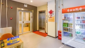 A hotel lobby with a reception desk, a vending machine, an elevator, and a refrigerator stocked with beverages. - 7 Days Premium Beijing Changping Subway Station (Changping)