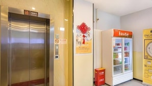 An elevator, a refrigerator, and a poster on a wall. - 7 Days Premium Beijing Changping Subway Station (Changping)