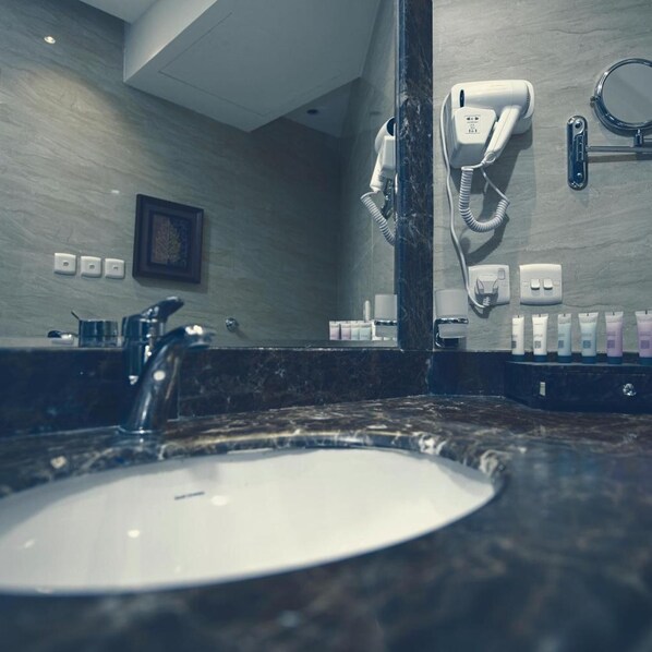 Une salle de bain avec un lavabo en marbre, un sèche-cheveux et un miroir.