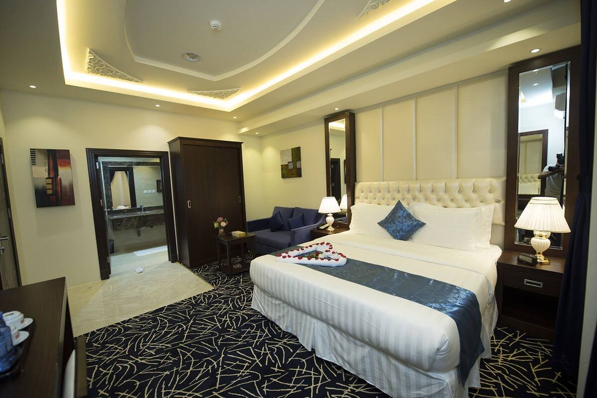 A hotel room with a large bed, a sofa, a desk, and a mirror.