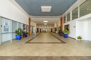 A spacious hallway with a tiled floor, potted plants, and a sign indicating Medicare walk-in services.