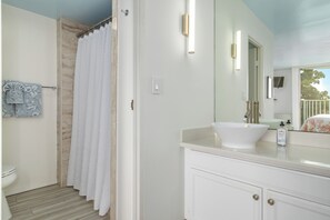 A bathroom with a white sink, a mirror, a shower curtain, and a towel rack with patterned towels.