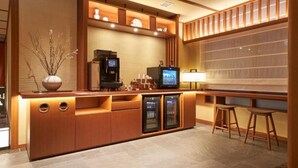 A modern bar area with a wooden counter, a coffee machine, a television, and two stools. - Shijo Kawaramachi Onsen Soraniwa Terrace Kyoto (Kyoto)