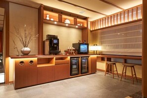 Eine moderne Bar mit einer Holztresen, einer Kaffeemaschine, einem Fernseher und zwei Barhocker.