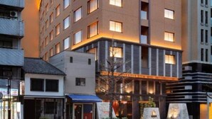 A modern hotel with a curved facade, multiple floors, and illuminated windows. - Shijo Kawaramachi Onsen Soraniwa Terrace Kyoto (Kyoto)