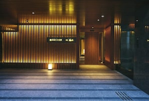 A modern building entrance with a wooden slat wall, a lit sign, and a staircase leading inside. - Shijo Kawaramachi Onsen Soraniwa Terrace Kyoto (Kyoto)