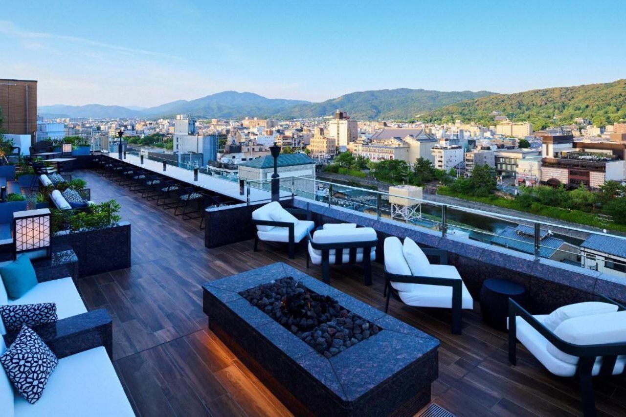 Terraza en la azotea con mobiliario exterior, un hogar a leña y vistas a la ciudad.