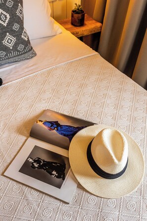 A bed with a patterned bedspread, a hat, and two magazines on it. - Skiathos Theros (Skiathos)